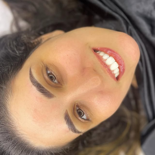 Mulher sorrindo com sobrancelhas micropigmentadas fio a fio.